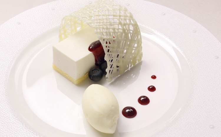 純白のレアチーズケーキにホワイトチョコレートのヴェールブルーベリーのピューレとアイスクリーム